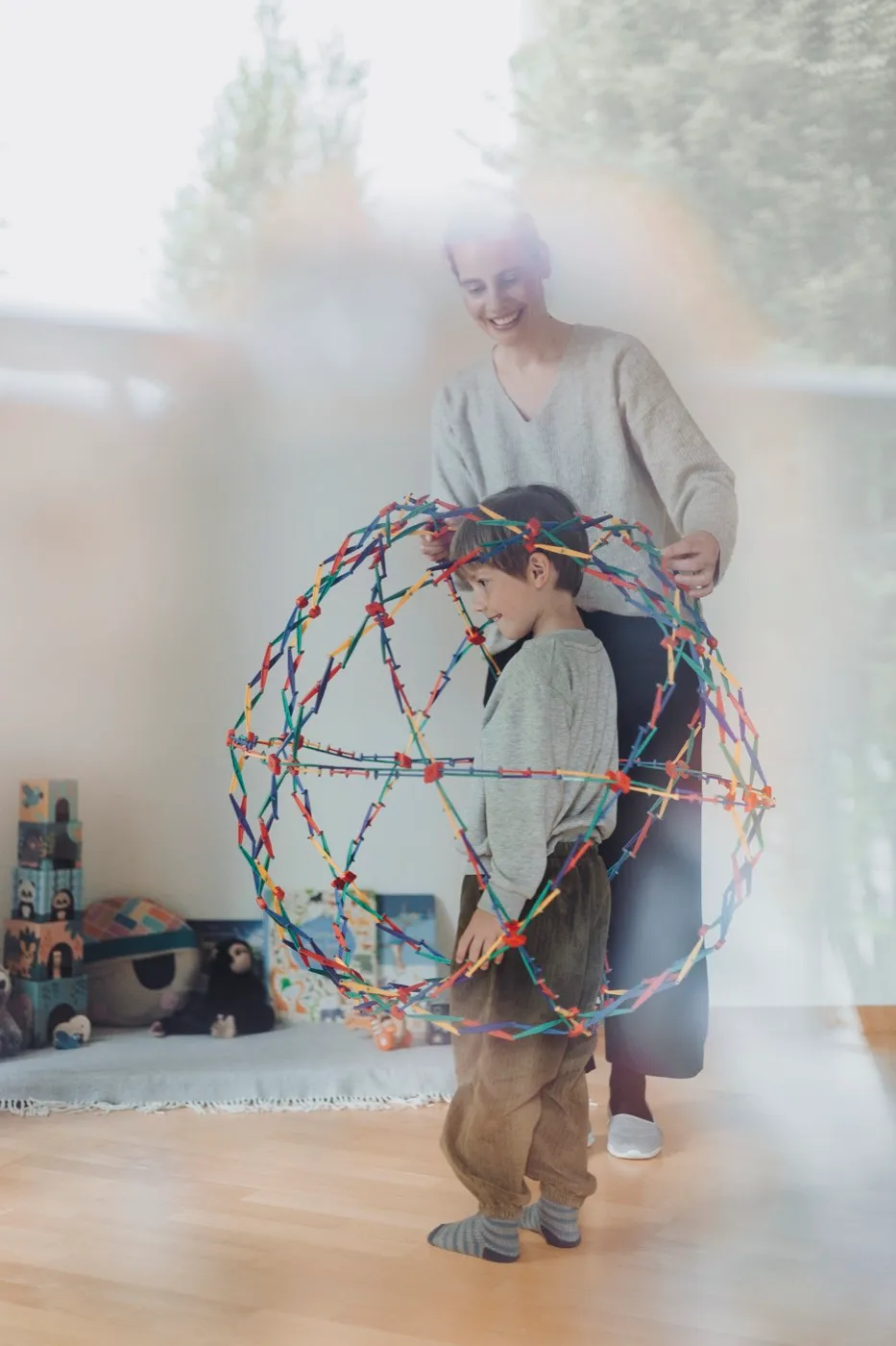Kind und Erwachsene spielen im Wohnzimmer mit einer grossen, faltbaren Konstruktionskugel