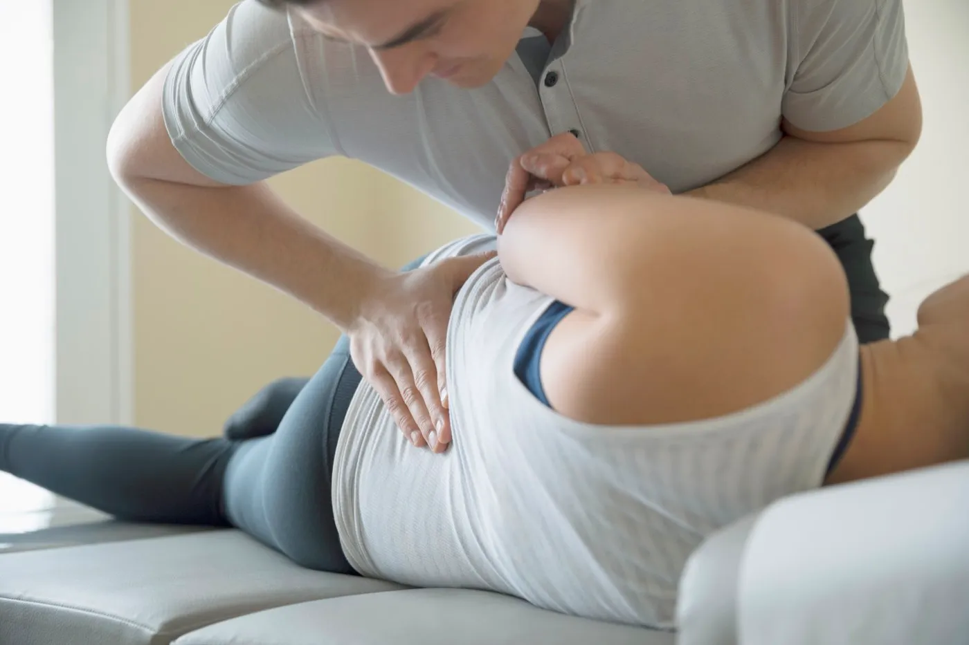 Therapeut arbeitet mit beiden Händen am Rücken einer seitlich liegenden Person
