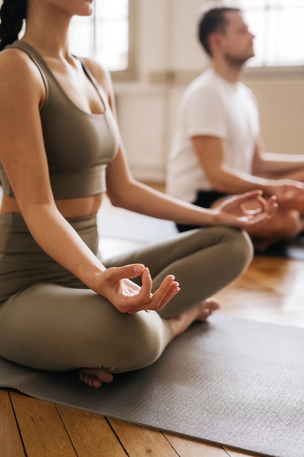 Zwei Personen sitzen im Schneidersitz auf Yogamatten und atmen ruhig