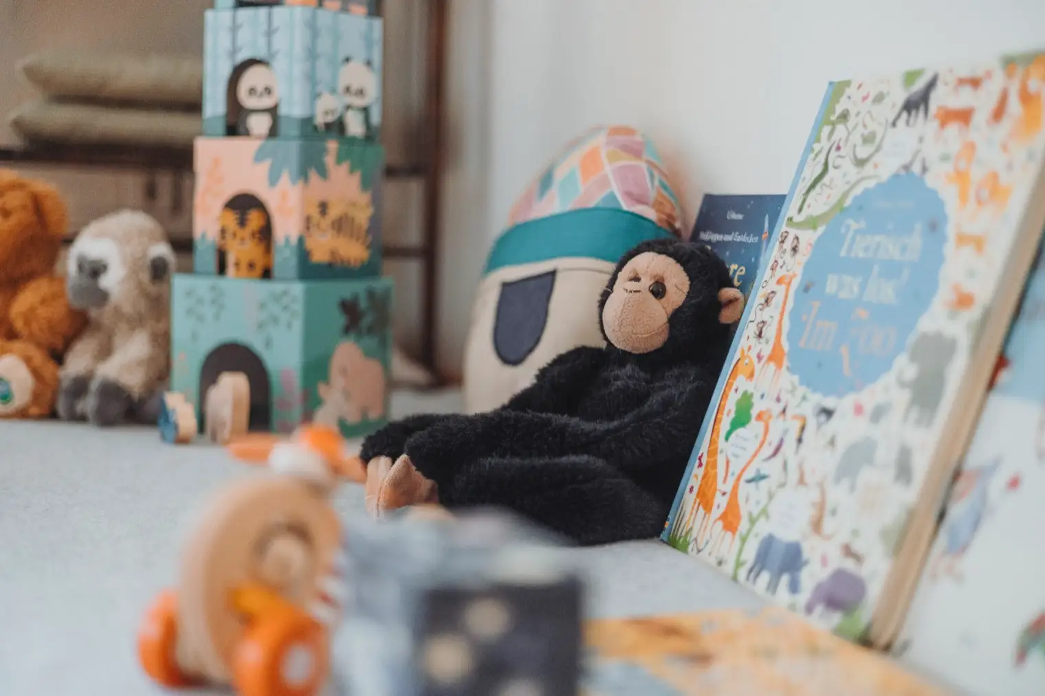 Kindgerechte Spielecke in der Praxis Zentral: Kuscheltiere, Stapelwürfel und Bilderbücher auf der Behandlungsliege.