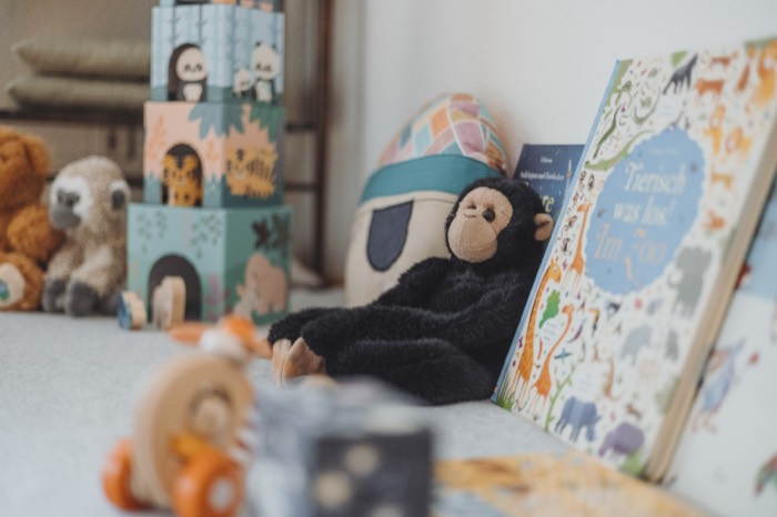 Kinderspielzeug auf der Behandlungsliege: Kuscheltiere, Stapelwürfel und ein Bilderbuch.